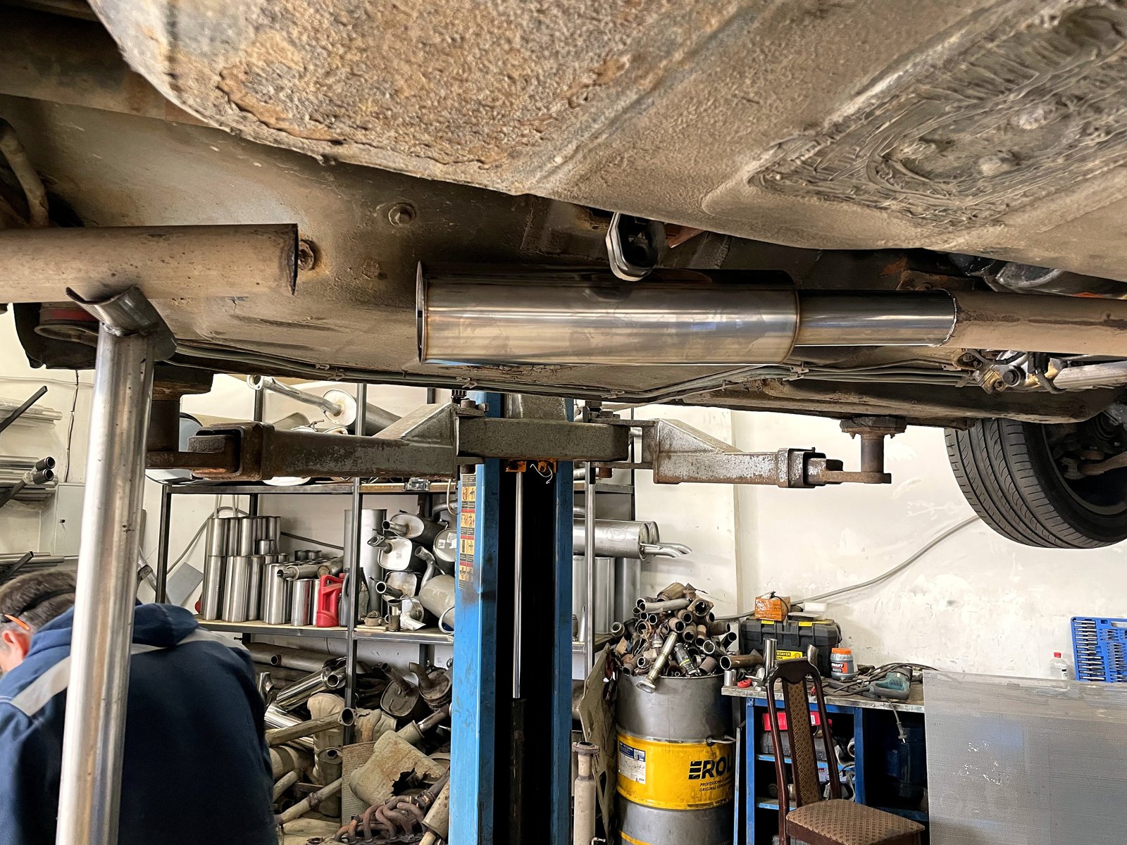 Новый нержавеющий резонатор подвешен по месту под днищем BMW E34, стык с трубой ещё открыт