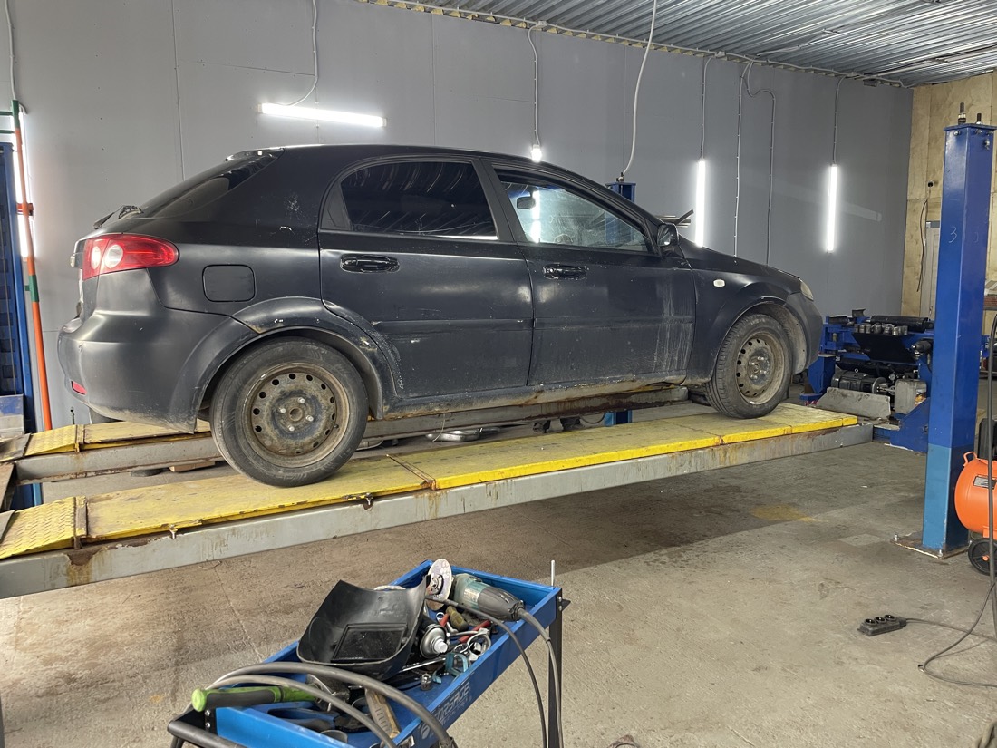 Чёрный Chevrolet Lacetti хэтчбек поднят на подъёмнике в боксе «Выхлопухи»