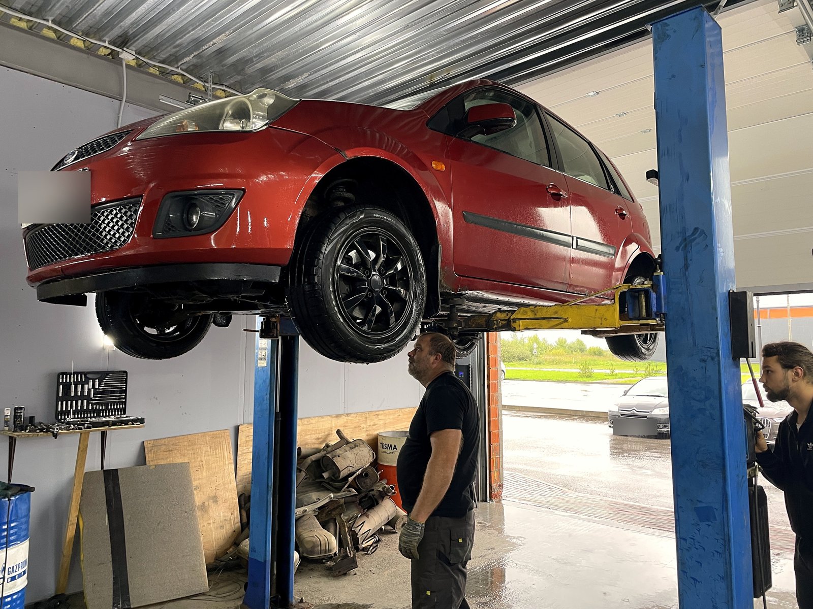 Красная Ford Fiesta на подъёмнике в боксе «Выхлопухи», вид спереди, госномер замазан