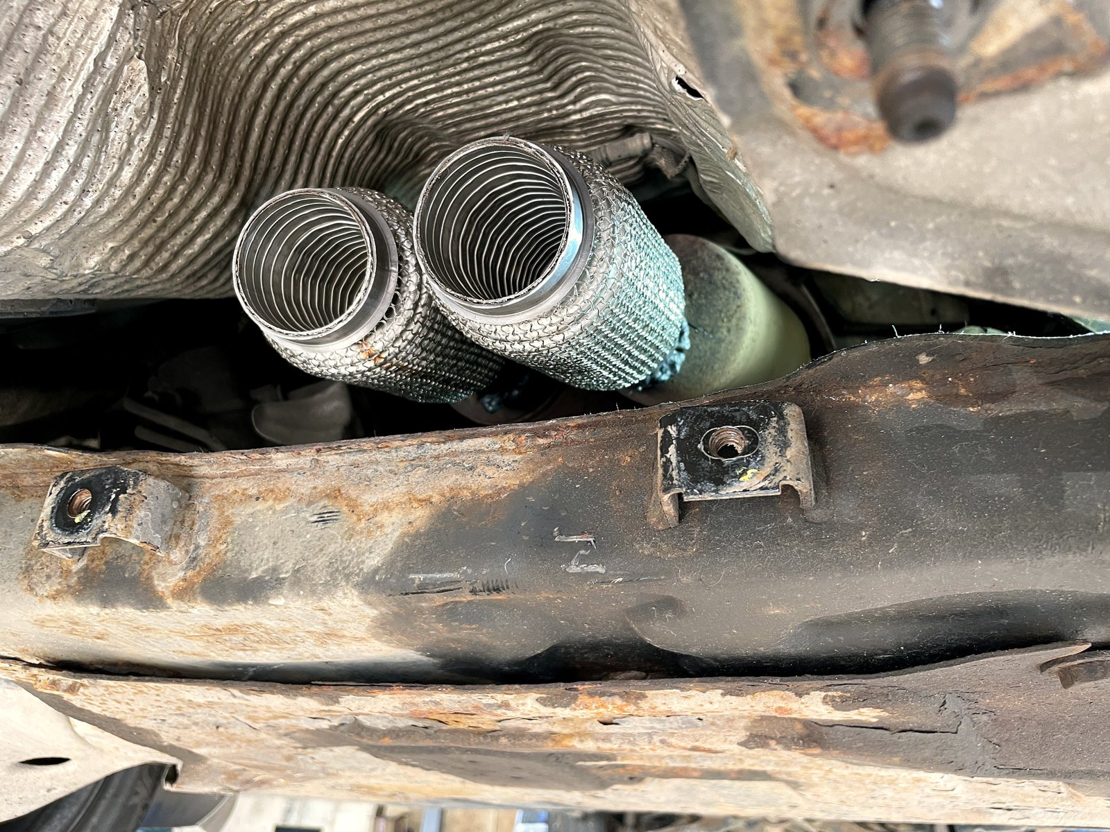 Две новые блестящие гофры приёмной трубы Ford Focus 3 стоят на месте, вид снизу