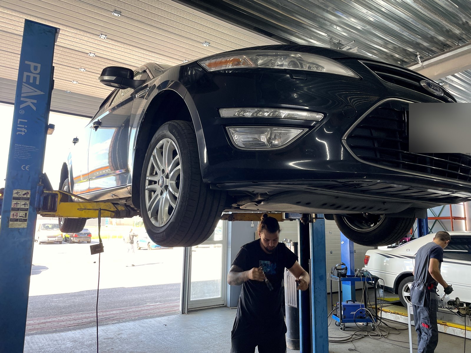 Ford Mondeo на подъёмнике в боксе «Выхлопухи», вид спереди снизу, номер замазан