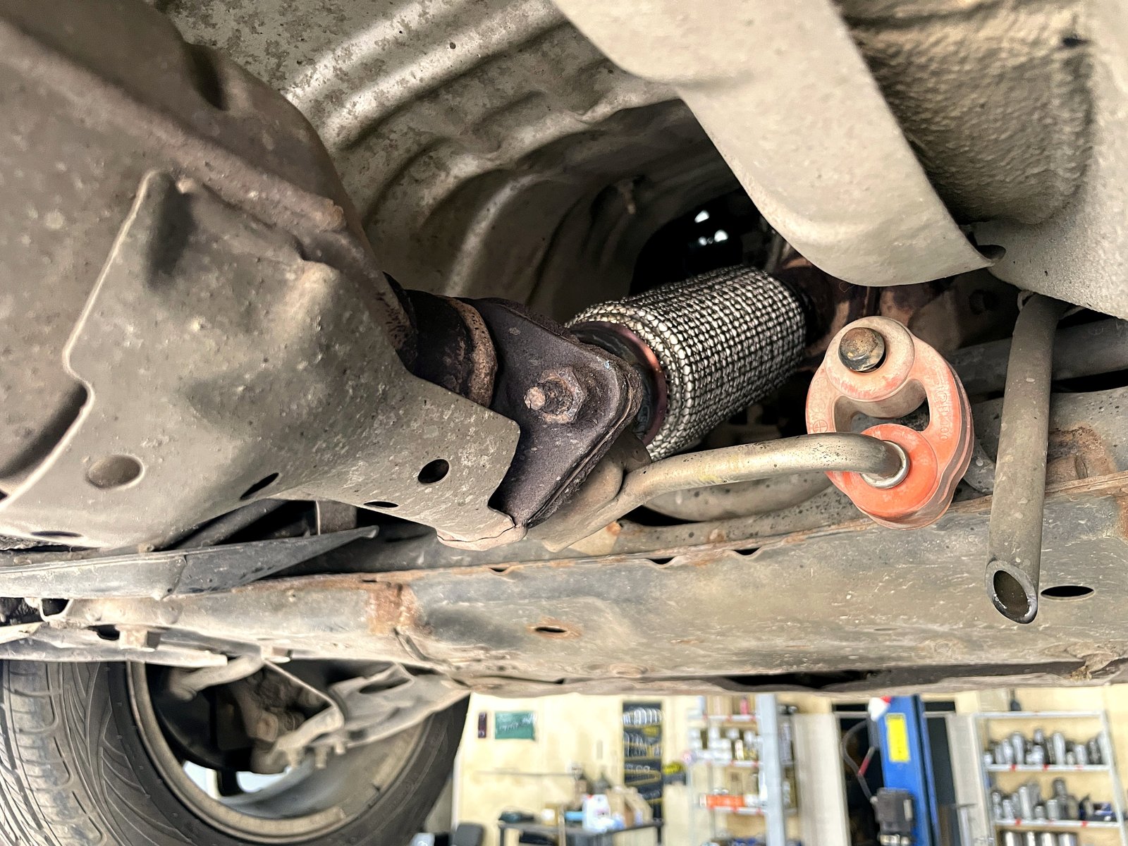 Новая гофра в выхлопной трассе Kia Ceed под днищем, рядом резиновая подушка подвеса