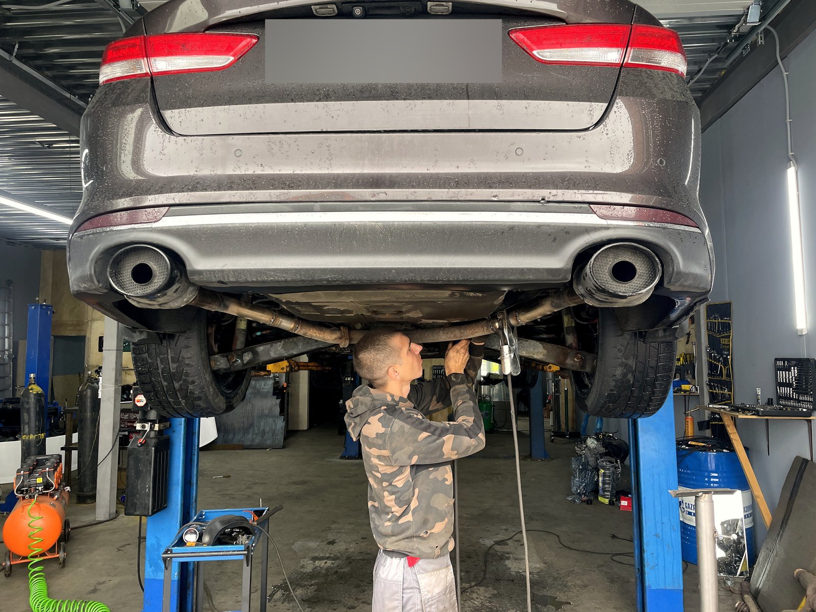 Задняя часть Kia Optima со штатным выпуском после работы, вид снизу на подъёмнике