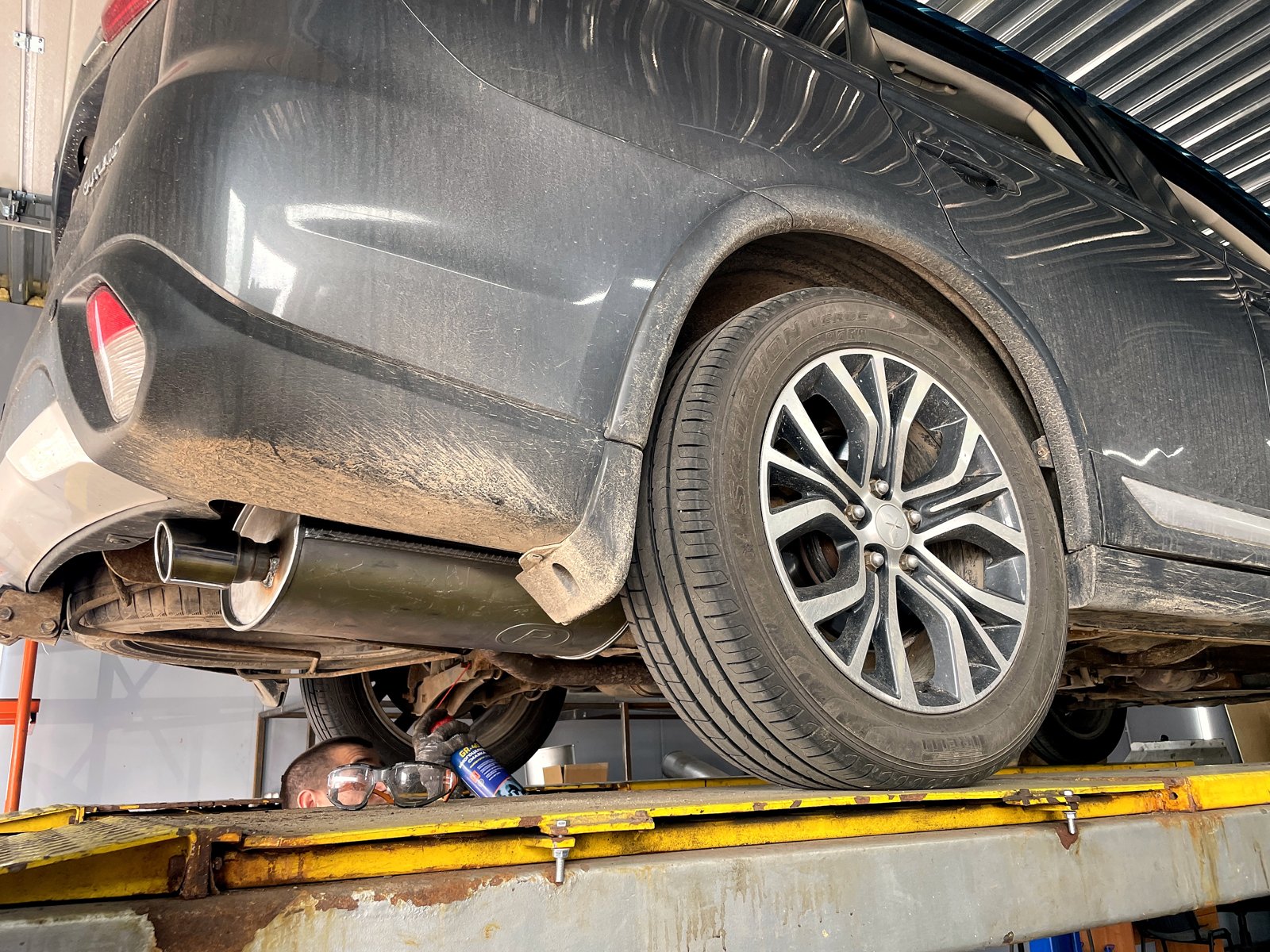 Mitsubishi Outlander на подъёмнике в боксе «Выхлопухи» после замены банки, из-под бампера выходит новая блестящая насадка