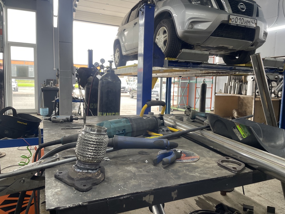 Новая блестящая нержавеющая гофра на приёмном фланце выхлопа Nissan Terrano на верстаке
