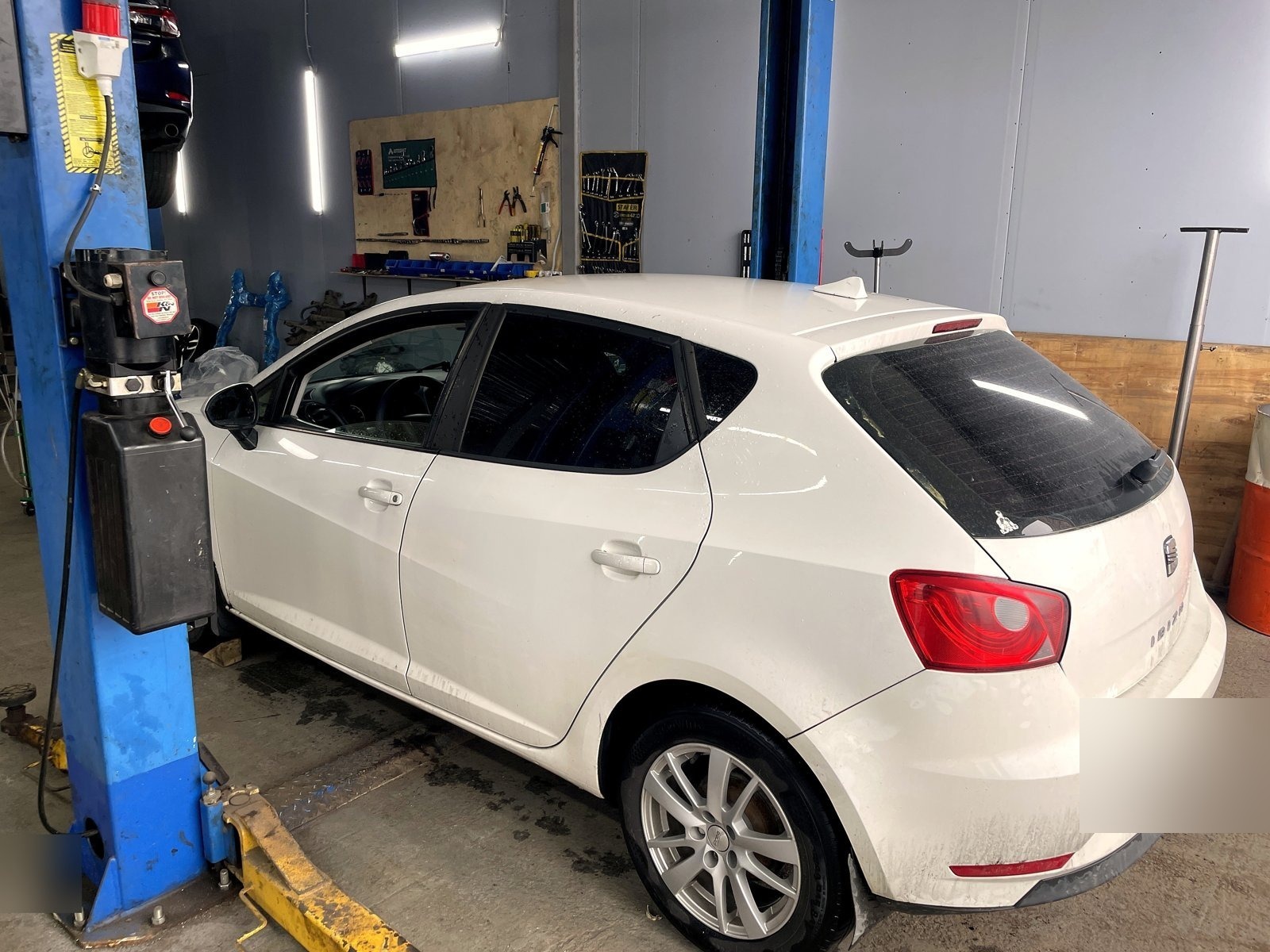 Белый SEAT Ibiza стоит готовый после ремонта на подъёмнике в боксе «Выхлопухи»