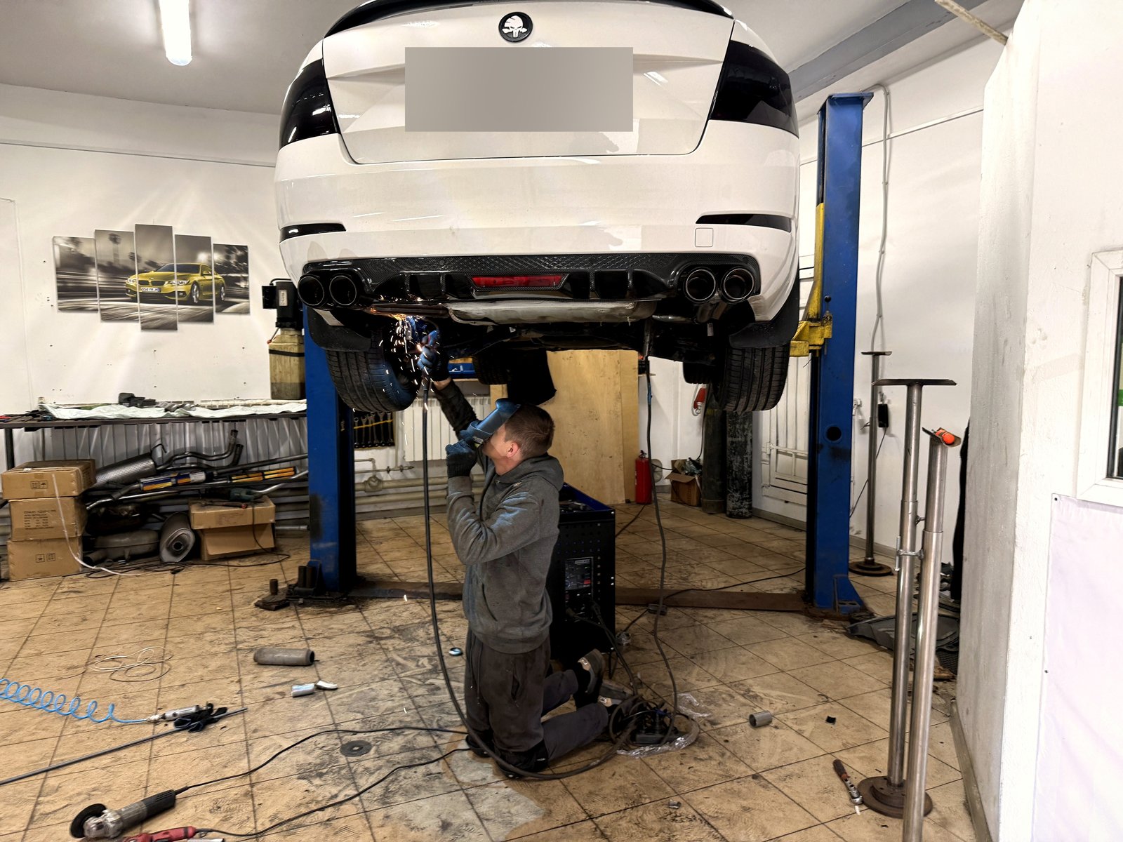 Белая Skoda Octavia на подъёмнике после работы: в диффузоре под карбон по паре чёрных насадок с каждой стороны
