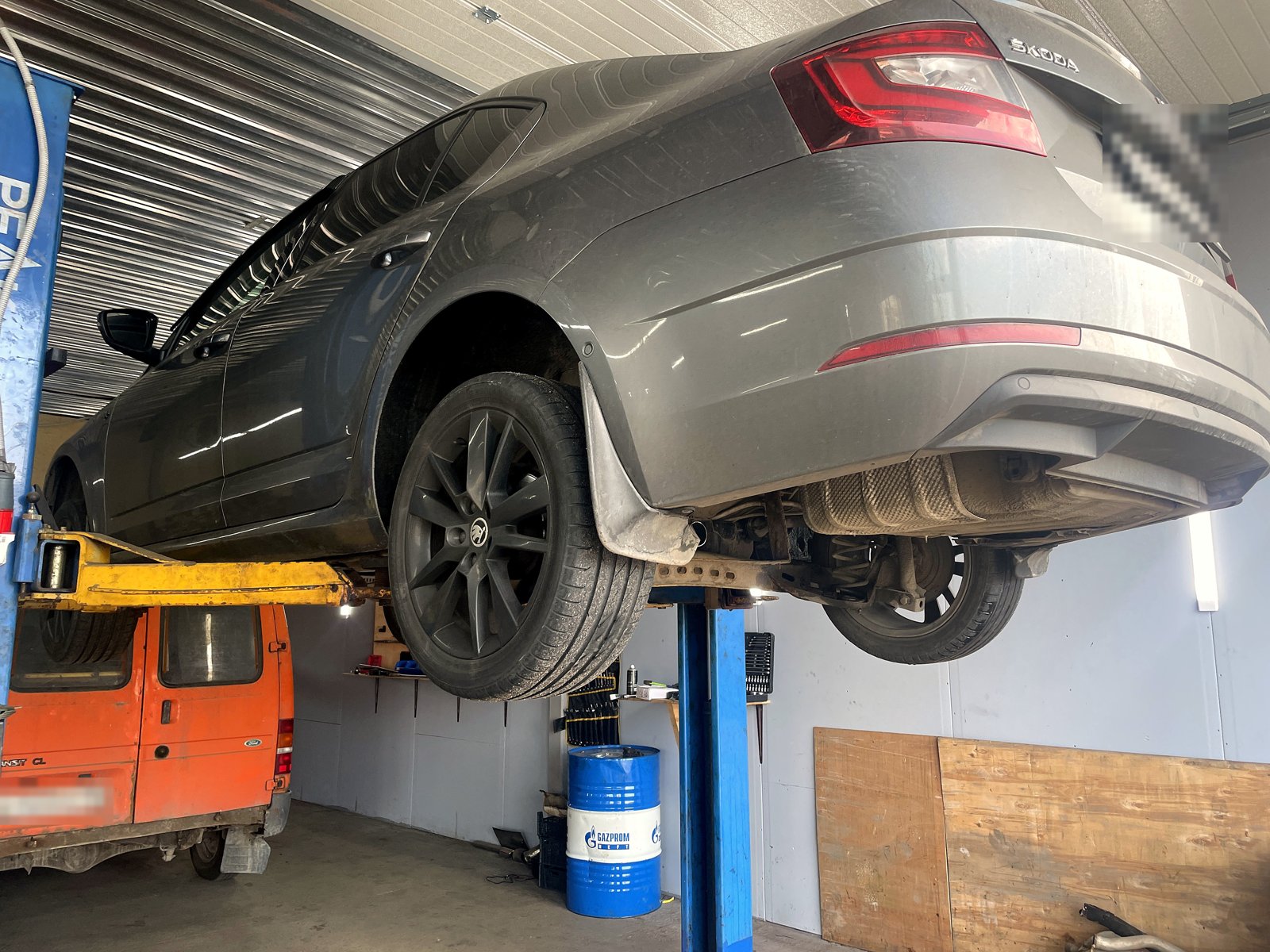 Задняя часть Skoda Octavia на подъёмнике, снизу видно место, откуда снят глушитель