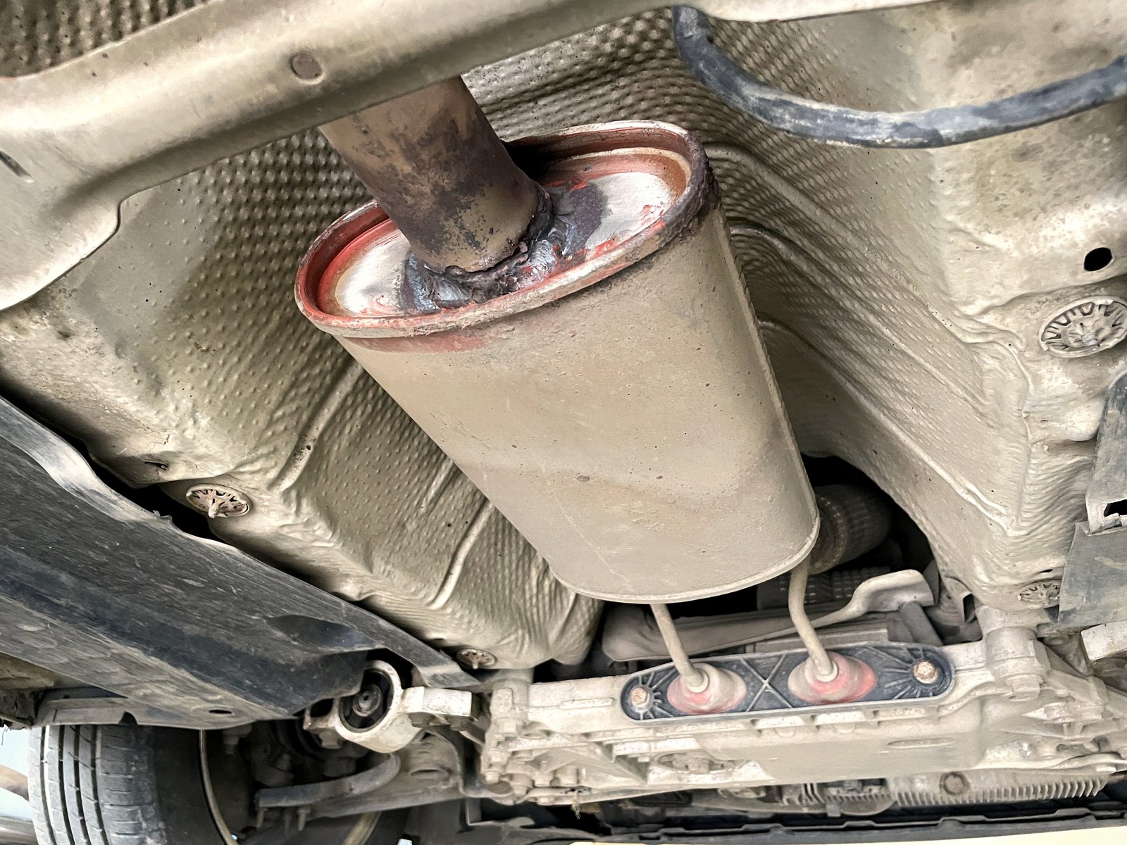 Крупный план старого пустого корпуса катализатора VW Passat B6, вход трубы со следами старой сварки