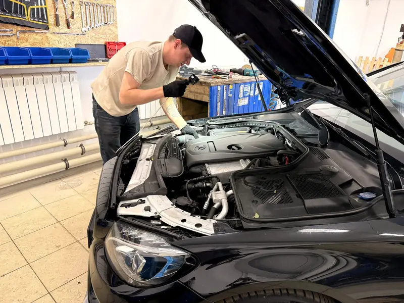 Мастер «Выхлопухи» проводит диагностику Mercedes с открытым капотом