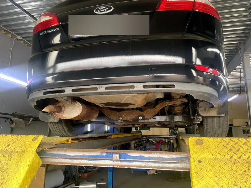 Ford Mondeo 4 седан поднят на подъёмнике в боксе «Выхлопухи», вид сзади снизу, номер замазан