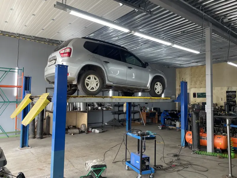 Серебристый Nissan Terrano на подъёмнике в боксе «Выхлопухи», вид сзади сбоку