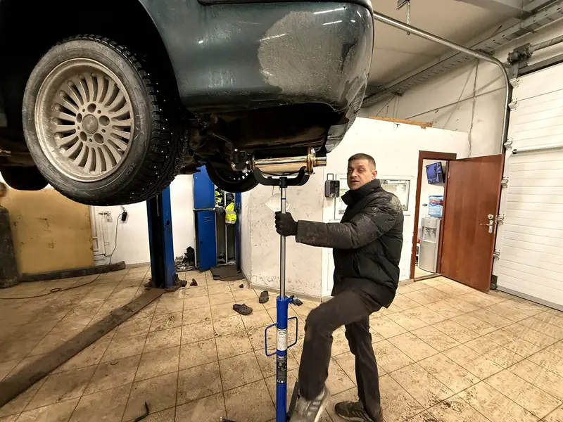 Мастер «Выхлопухи» подводит новую банку из нержавейки на стойке под BMW E39 на подъёмнике