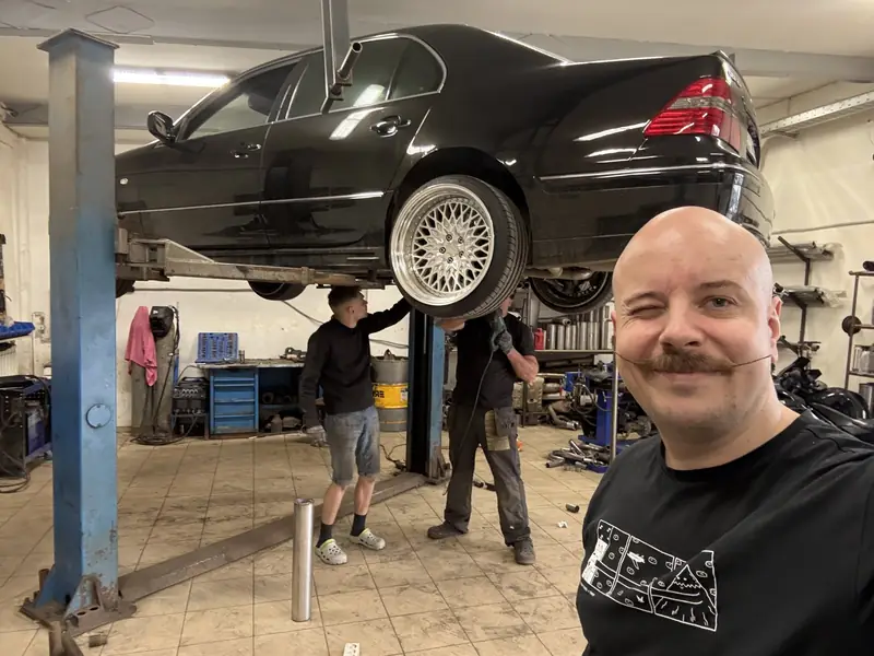 Чёрный Lexus LS430 на подъёмнике в боксе «Выхлопухи», мастер на переднем плане
