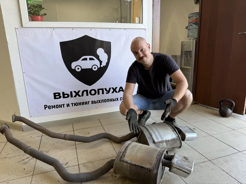 Снятая выхлопная система BMW X5 с двумя банками у баннера «Выхлопуха»